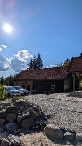 a building with a pile of rocks in front of a driveway at Król Puszczy - unikatowy dom, jezioro 80m, szlak Krutyni in Ruciane-Nida