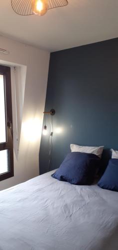 une chambre avec un grand lit avec un mur bleu dans l'établissement Appartement terrasse au cœur de Pont l'Abbé, à Pont-lʼAbbé
