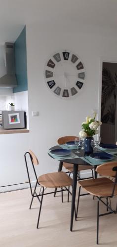 une table à manger avec des chaises et une horloge murale dans l'établissement Appartement terrasse au cœur de Pont l'Abbé, à Pont-lʼAbbé