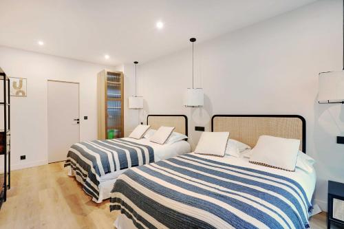 deux lits dans une chambre aux murs blancs dans l'établissement Spacious Apartment - 2BR-10P - Place d'Italie, à Paris