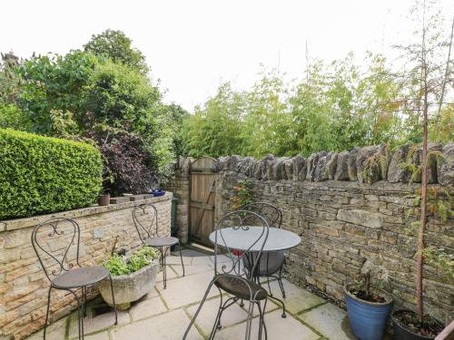 a patio with two tables and chairs and a stone wall at The Lodge in Quenington