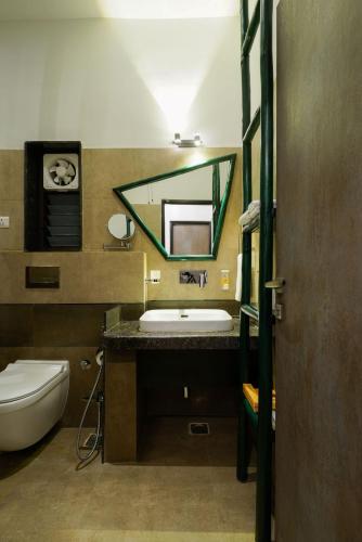 a bathroom with a sink and a toilet and a mirror at Tathastu Kanha in Kānha