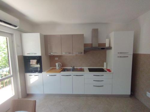 a white kitchen with white cabinets and a sink at Apartman Kora in Njivice