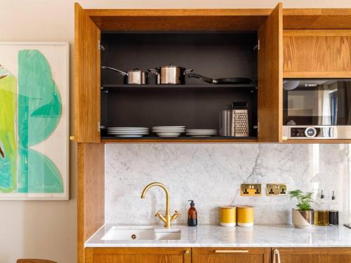 a kitchen with a sink and a shelf with pots and pans at Luxury Apartments in a vibrant part of North London in London