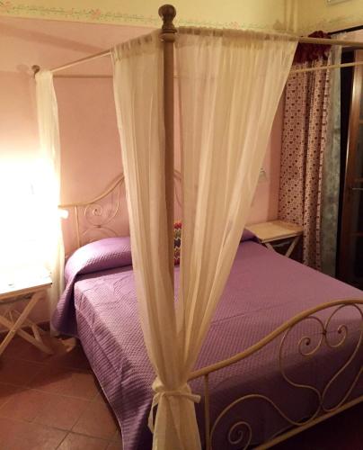 a bedroom with a canopy bed with purple sheets at B&B 8380 Saturnia Terme in Saturnia