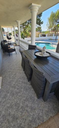 a wooden table and chairs on a patio with a pool at Apartment in big house with private pool & large outdoor space in L'Alfas del Pi