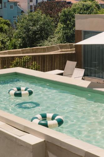 a swimming pool with two lawn chairs and two swimming tubes at JAM Porto in Porto