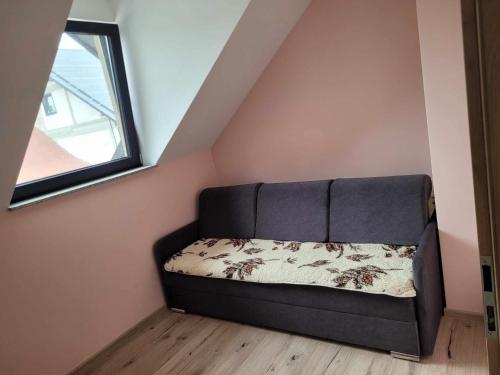 a couch in the corner of a room with a window at Apartament Fort 206 in Ujkowice