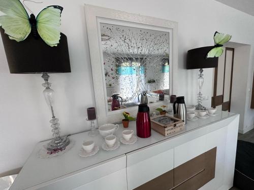 - une commode blanche avec un miroir et des papillons dans l'établissement La Villa Martinière, à Bièvres