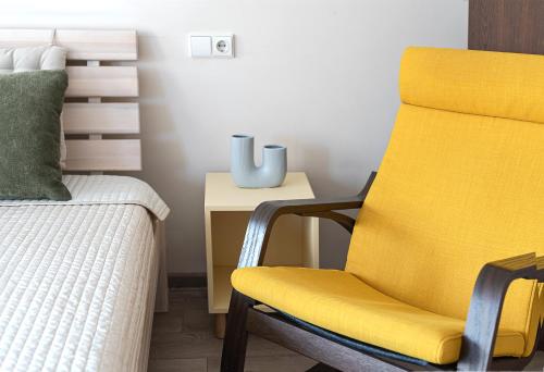 a bedroom with a yellow chair next to a bed at Algirdo Apartments, Self Check-in, Free Private Parking in Vilnius