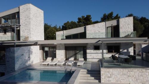 a building with a swimming pool in front of it at Alessandra Luxury Villas with Private Pools and Jacuzzi in Kriopigi