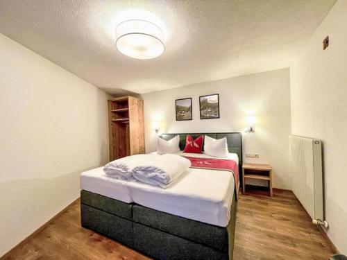 a bedroom with a bed with white sheets and red pillows at Apartment Panorama by Interhome in See