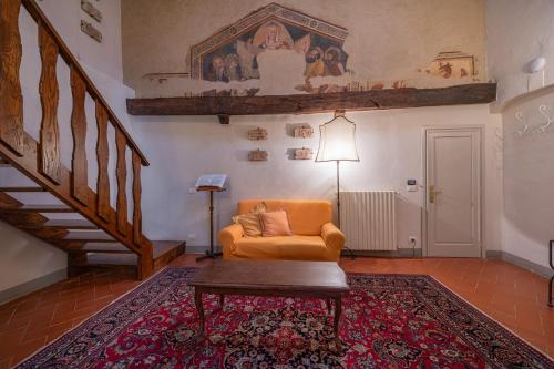 a living room with an orange chair and a staircase at Hotel San Michele in Cortona