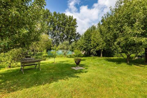 a park with a bench and a grill in the grass at Vakantiehuis Wandelen en fietsen in de Kalkense Meersen dichtbij Gent in Laarne