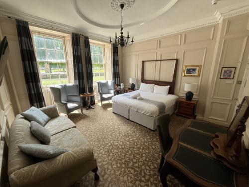 a bedroom with a bed and a couch and a chair at Manor House Hotel in Bishop Auckland
