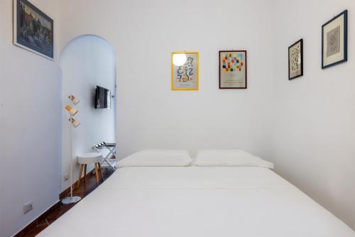a white bed in a white room with pictures on the wall at La Casetta in Rome
