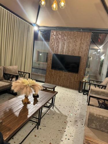 a living room with a wooden table and a flat screen tv at شاليهات جولدن الفندقية in Al-Salam