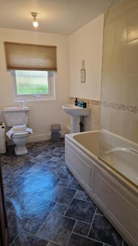 a bathroom with a tub and a toilet and a sink at Meikle Farm Cottage in Westruther