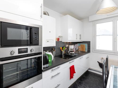 une cuisine avec des armoires blanches et un micro-ondes dans l'établissement Apartment La Ville Allis by Interhome, à Saint-Malo