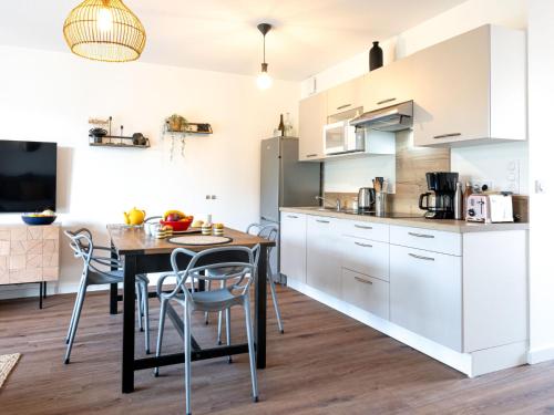 a kitchen with white cabinets and a table and chairs at Apartment Jade et Elena-3 by Interhome in Lit-et-Mixe