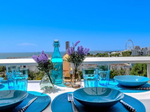une table avec des assiettes et des verres bleus sur un balcon dans l'établissement Studio Les Terrasses de la Mer-18 by Interhome, à La Grande Motte
