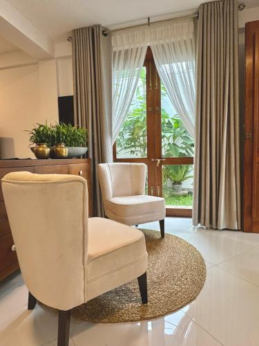 a living room with two chairs and a window at Villa Vikasa Colombo in Colombo