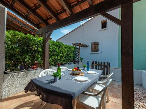 une table avec des chaises blanches et une nappe bleue sur une terrasse dans l'établissement Holiday Home le Hameau Catalan-2 by Interhome, au Barcarès