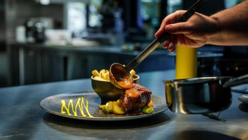 a person holding a spoon over a plate of food at Hotel La Reserve in Sankt Niklaus