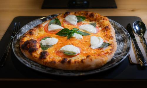 a pizza sitting on a plate on a table at Hotel La Reserve in Sankt Niklaus