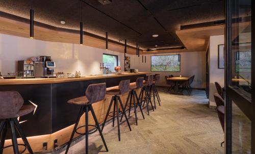 a bar with stools in a room with tables at Hotel La Reserve in Sankt Niklaus