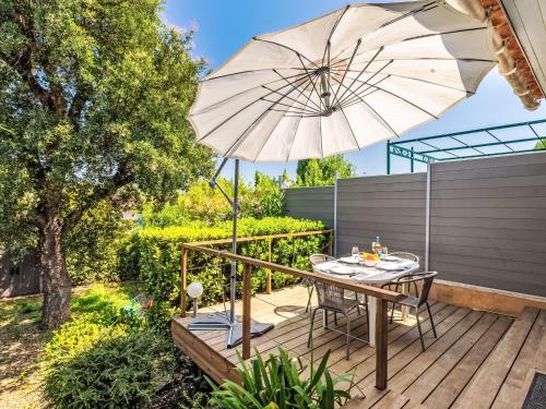une terrasse en bois avec une table et un parasol dans l'établissement Holiday Home Font Mourier-1 by Interhome, à Gassin