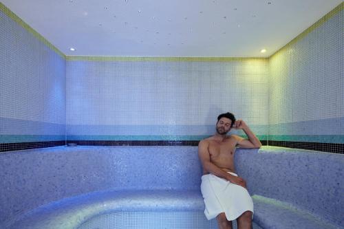 a man sitting in a tub in a bathroom at Parkhotel Gütersloh in Gütersloh