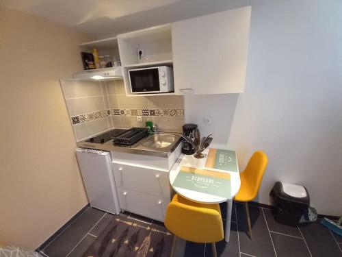 une petite cuisine avec une petite table et des chaises jaunes dans l'établissement Residence de l'évèché 9, à Limoges