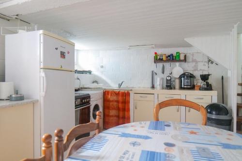 une cuisine avec une table et un réfrigérateur blanc dans l'établissement Maison mitoyenne cœur de ville à deux pas du port de pêche et de la plage Les Sables - 6 personnes, à Les Sables-dʼOlonne