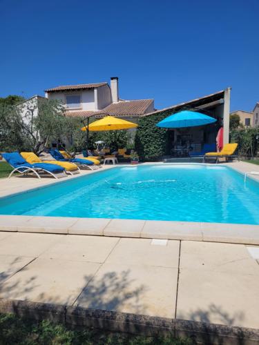 une piscine avec chaises et parasols dans l'établissement maisonnette avec piscine la picholine, à Châteaurenard
