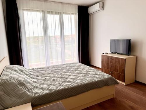 a bedroom with a bed and a tv and a window at Sunset studio in Shartrez in Shkorpilovtsi