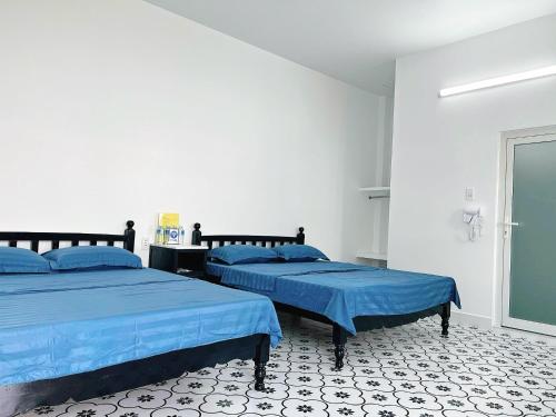two beds in a white room with blue sheets at SIGNATURE by LAZÁNIA in Tây Ninh