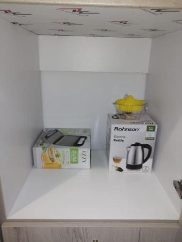 a white shelf with two boxes and a coffee maker at Natalia's Serene Hub in Aegina Town
