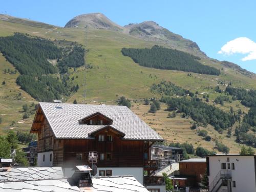 a house in a village with a mountain in the background at Au Coeur De La Station in Les Deux Alpes