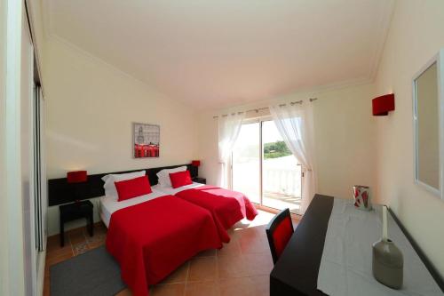 a bedroom with two beds with red sheets and a window at Bela Vivenda-pretty Family Villa With Pool & Golf in Castro Marim
