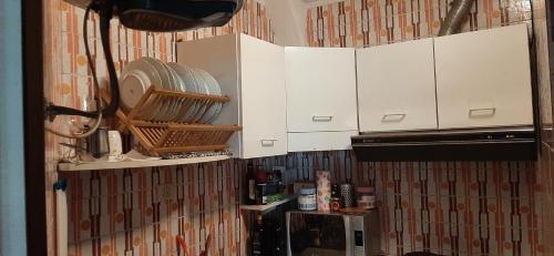a kitchen with white cabinets and plates on the wall at La tana del lupo Pet Free in Terminillo