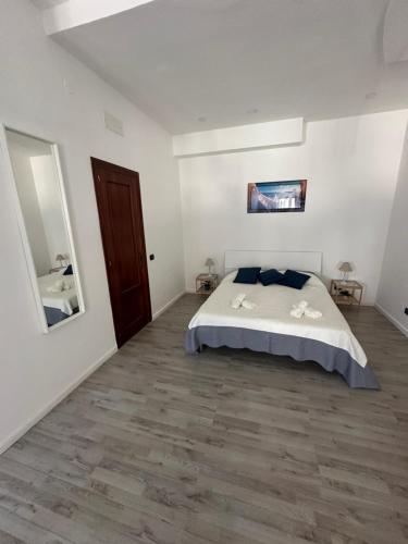 a white bedroom with a bed and a wooden floor at Maison Margot in Pozzuoli