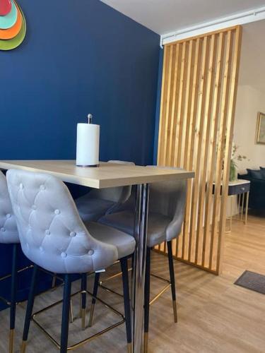une table avec des chaises bleues et un mur bleu dans l'établissement Luxury-Jo Appartement Complet Moderne 4 Chambres, à Roanne