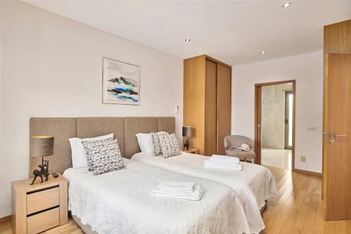 a white bedroom with a large bed and a chair at Stylish Townhouse In Tavira Centre, Shared Pool in Tavira