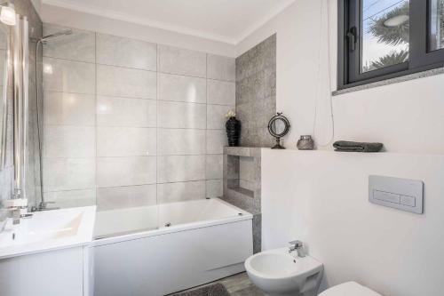 Un baño con bañera, lavabo e inodoro. en Villa Oceanscape, en Madalena do Mar
