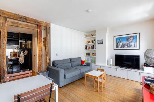 un salon avec un canapé et une télévision dans l'établissement GuestReady - Confort et Élégance au Cœur de Paris, à Paris