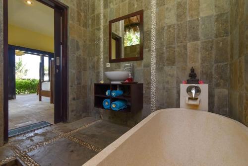 a large bathroom with a tub and a sink at North Bali Beachhouse Ayu in Umeanyar