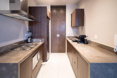 a kitchen with wooden cabinets and a counter top at PENINSULA STAYS 2 BR Designer Apartment & 200 MB FAST WIFI New Listing! in Mérida