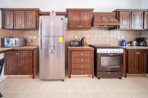 a kitchen with wooden cabinets and a stainless steel refrigerator at PENINSULA STAYS 4BR Beach House @ PROGRESO The Best Location in the Yucatan in Progreso