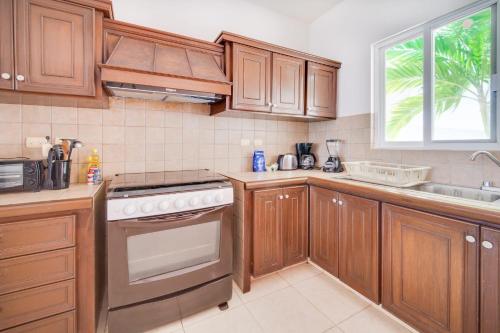 a kitchen with wooden cabinets and a white stove top oven at PENINSULA STAYS 4BR Beach House @ PROGRESO The Best Location in the Yucatan in Progreso